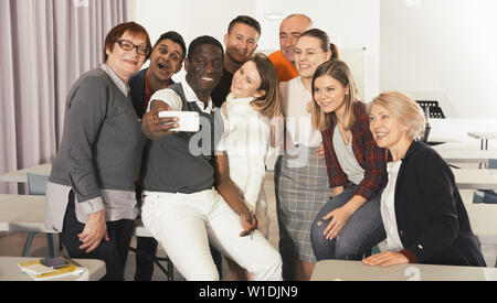 Multinational group of of happy adult students taking selfie in auditorium Stock Photo