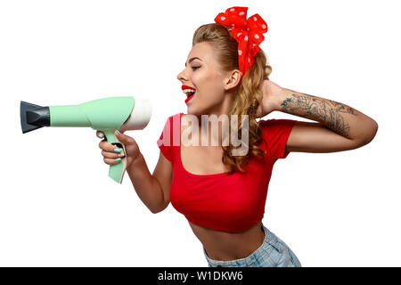 Half body portrait of young woman with tattoo in red vintage clothes pointing hairdryer Stock Photo