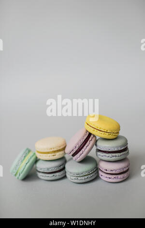 Sweet colorful pile of French macaroon biscuits lying on pastel grey background. Stock Photo