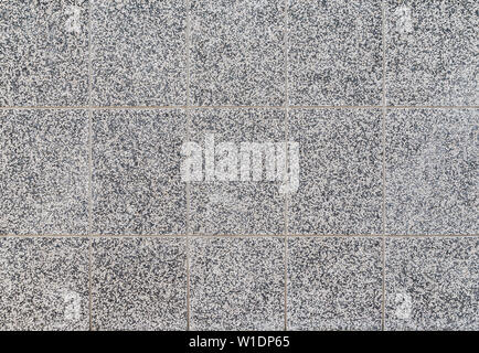 High resolution full frame textured background of a building exterior wall with small mixed black and white pebbles. Stock Photo