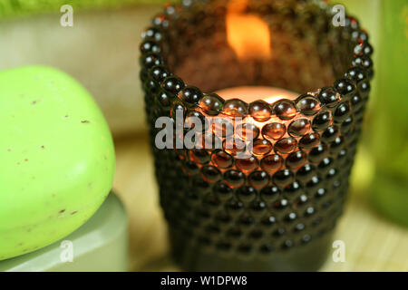 Brown textured tealight holder with burning candle in green spa treatment Stock Photo