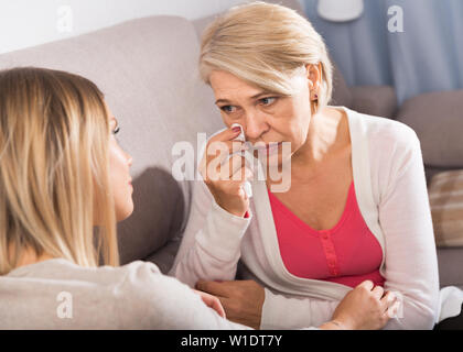 An adult good daughter comforts her sad elderly mother Stock Photo