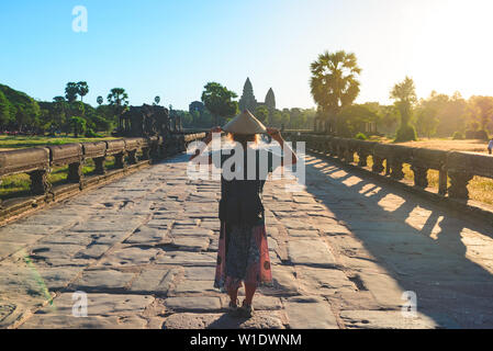 Woman in Bayon Temple looking at stone faces, Angkor Thom, morning light clear blue sky. Buddhism meditation concept, world famous travel destination, Stock Photo