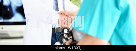 Two doctors in office shaking hands celebrating successful treatment Stock Photo