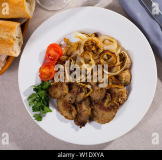 Tasty rabbit liver fried with onion garnished with fresh parsley and blanched cherry tomatoes Stock Photo