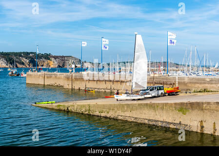 Morgat, France - August 4, 2018:  People taking out the water and storing canoes, kayaks and a catamaran in the marina of Morgat a sunny day of summer Stock Photo