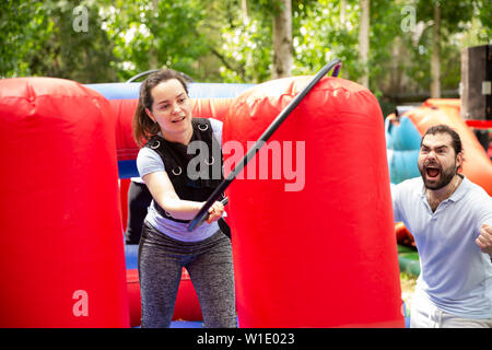 Portrait of emotional young woman putting hoop on inflatable pole during competition in outdoor amusement park Stock Photo