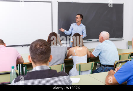 Adult lecturer talking to mixed age  students during seminar Stock Photo