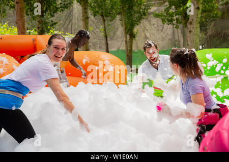 Friendly multiracial team having funny competition in collect of balls in inflatable foam pool on adults bouncy playground Stock Photo