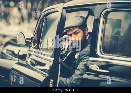Confident wealthy young man with beard in classic car Stock Photo