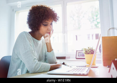 Bored female student looking at laptop studying from home Stock Photo