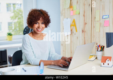 Successful young woman working on laptop in office Stock Photo