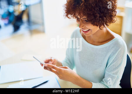 Happy young woman using her smartphone - selective focus Stock Photo