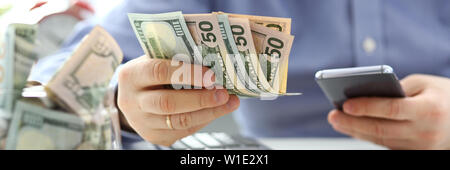Male hand holding pack of banknotes and cellphone Stock Photo