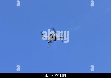 Drone flying against a blue sky Stock Photo