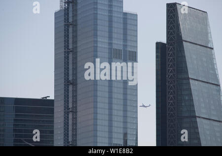London, UK. 2nd July 2019. Warm start to the day in central London, a plane approaching London docklands airport seen through office skyscrapers at 122 Leadenhall Street (‘The Cheesegrater’) and 22 Bishopsgate (Twentytwo) in the City of London. Credit: Malcolm Park/Alamy Live News. Stock Photo