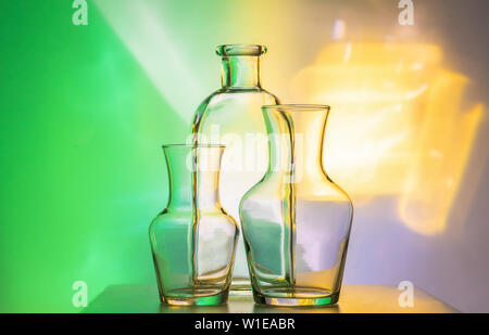 Glass transparent tableware - bottles of different sizes, three pieces on a beautiful multi-colored, yellow, and green, background. very beautiful Stock Photo
