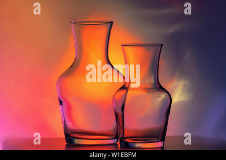 glass transparent tableware - bottles of different sizes, three pieces on a beautiful multi-colored, yellow, lilac and pink, background. very Stock Photo