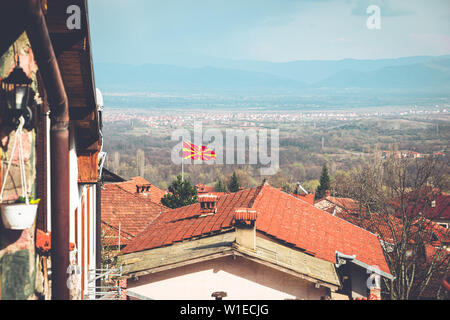 A Macedonian flag over the rooftops of a traditional rural village in the mountains of Macedonia Stock Photo