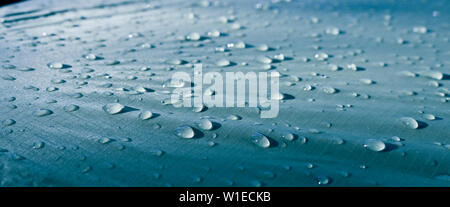 Large drops of water on Cyan textiles with a waterproof effect. Water-repellent impregnation. Texture drops on the fabric. Selective focus Stock Photo