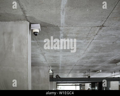 CCTV camera installed on concrete ceiling in the parking lot with copy space. Stock Photo