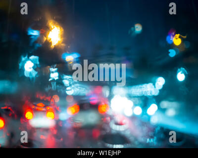 Blurred rain drops on car window with road light bokeh on rainy season ...