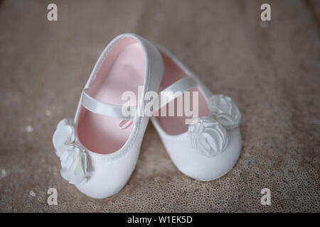 Elegant white ballerina shoes  adorable footwear for little girls or baby girl booties with white chiffon flowers and elasticated support strap Stock Photo
