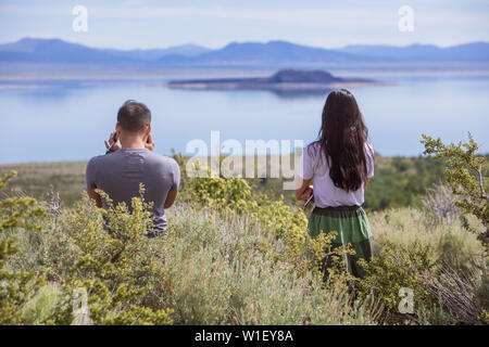 Couple from behind looking towards Paoha Island in Mono Lake Park viewed from Mono Basin Visitor Centre, Lee Vining, California, USA Stock Photo