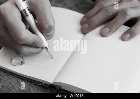 Hand writing white pen notebook with diamond ring in memory Stock Photo
