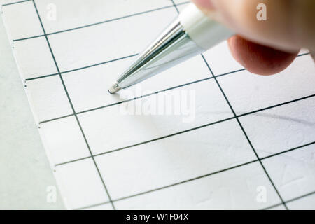 Right hand holding a pen signing on paper square Stock Photo