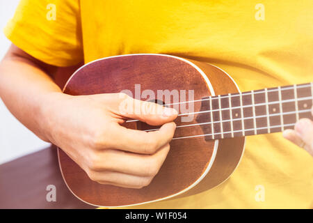 Young playing wooden ukulele shiny Stock Photo