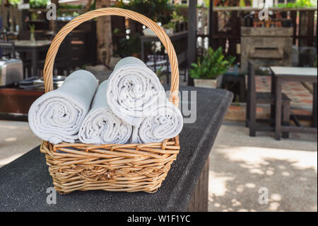 Folded roll towels stacked in wooden basket on the counter Stock Photo