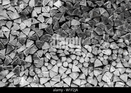 Background of splitted, dried and stacked firewood. Bunch of wood. Black and white photo. Stock Photo