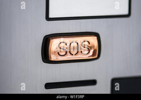 button SOS.  SOS button close-up on the device panel, intercom. Help call button on the screen of the device in gray metal color. Stock Photo