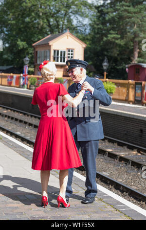 Kidderminster, UK. 29th June, 2019. Severn Valley Railways 'Step back to the 1940s' gets off to a fabulous start this weekend with costumed re-enactors playing their part in providing an authentic recreation of wartime Britain. A smartly-dressed, happy couple in 1940's fashion are dancing together on the platform of a vintage railway station in the morning sunshine. Credit: Lee Hudson Stock Photo