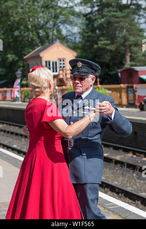 Kidderminster, UK. 29th June, 2019. Severn Valley Railways 'Step back to the 1940s' gets off to a fabulous start this weekend with costumed re-enactors playing their part in providing an authentic recreation of wartime Britain. A smartly-dressed couple in 1940's fashion are dancing together on the platform of a vintage railway station in the morning sunshine. Credit: Lee Hudson Stock Photo