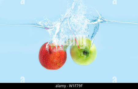 Red and green apples falling into water Stock Photo