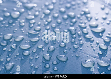 Large drops of water on Cyan textiles with a waterproof effect. Water-repellent impregnation. Texture drops on the fabric. Stock Photo
