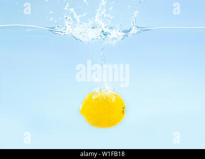 Fresh yellow lemon sinking deeply in clear water Stock Photo