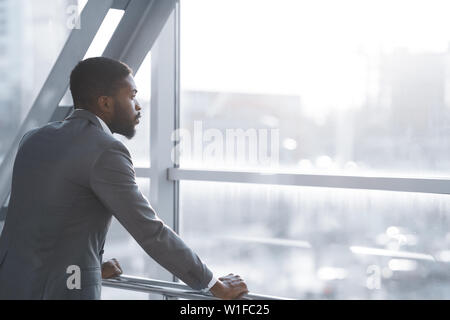 Wait for Flight. Afro Businessman Looking Through Window Stock Photo
