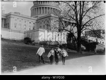 In comparison with governmental affairs, newsies are small matters. This photo was taken in the shadow where the laws are made. This group of young newsboys sell on the Capitol grounds everyday, ages 8, 9, 10, 11, 12, the only boy with a badge was 8 years old. Washington, D.C. Stock Photo