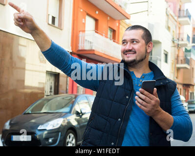 smiling man in city with phone in his hands outdoors Stock Photo