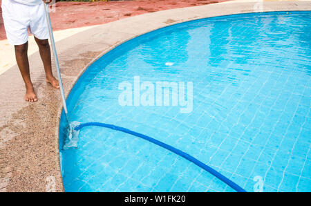 Man cleaning a swimming pool in summer. Cleaner of the swimming pool. Stock Photo