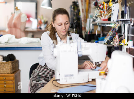 Young woman sewer working with modern sewing machine at workshop Stock Photo
