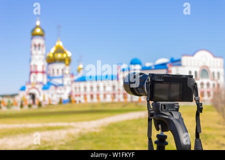 A camera with a large lens shoots a church on a clear summer day in a public park Stock Photo