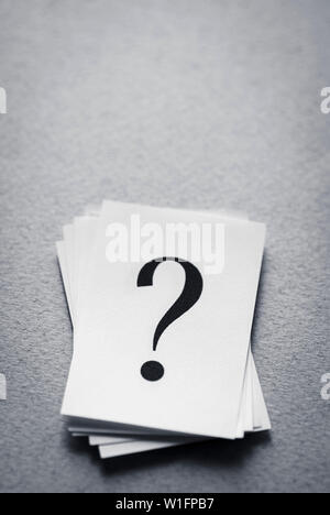stack of paper cards with a printed question mark on a gray background. Stock Photo