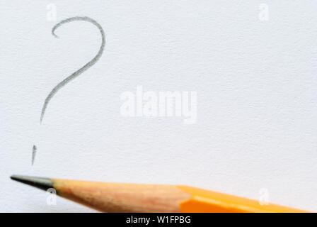 Sharp pencil lying next to question mark on white paper with copy space. Stock Photo