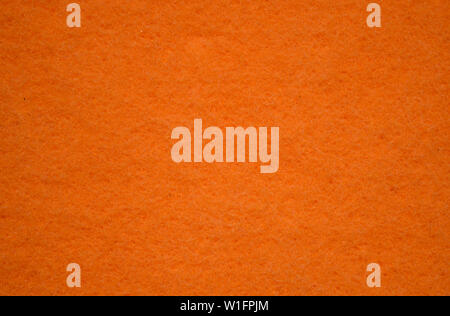 Texture of surface of unused orange sponge closeup. The concept of hygiene and cleanliness. Sponge for dishes, for cleaning. Close-up Stock Photo
