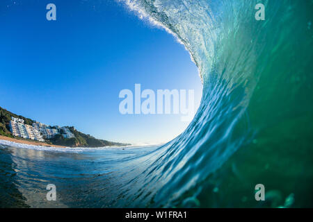 Ocean wave hollow swimming water photo of Surfer tube ride perspective inside out looking down towards the beach coastline. Stock Photo