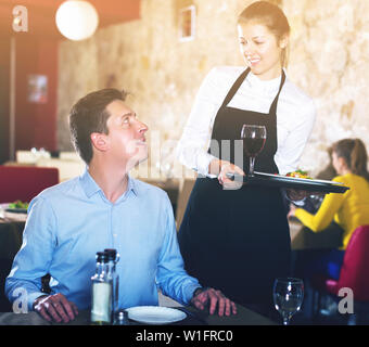 Waitressing Man waitress serving dishes to handsome man Stock Photo - Alamy